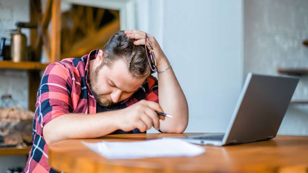 Photo of an exhausted man working at home before the deadline. - Valokuva, kuva