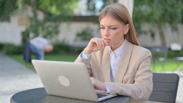 Femme d'affaires Penser et travailler sur ordinateur portable dans le café extérieur - Photo, image