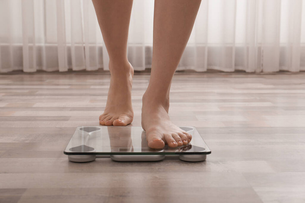 Woman stepping on floor scales indoors, closeup. Weight control - Photo, image