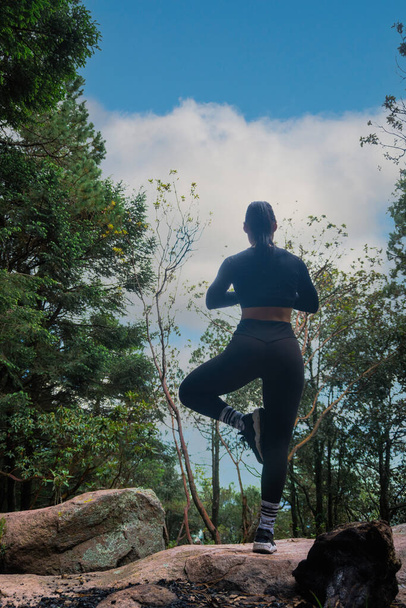 Een Jonge Spaanse vrouw oefent yoga op een klif in een bos - Foto, afbeelding