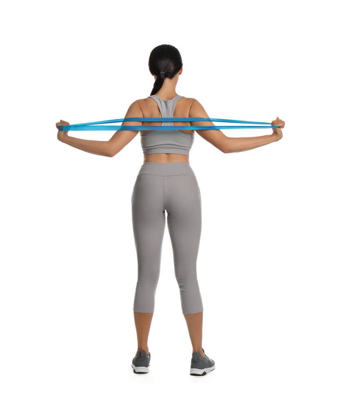 Woman doing sportive exercise with fitness elastic band on white background, back view - Foto, afbeelding