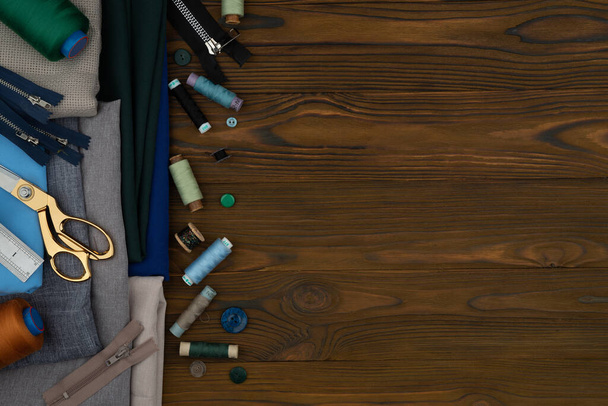 Knippen en naaien aangepaste kleding, naaien accessoires. Schaar, draden, stoffen op een houten tafel. Lege kopieerruimte - Foto, afbeelding