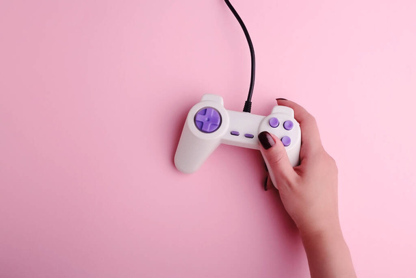 Žena drží video hry joystick na růžovém pozadí, detailní záběr. Hra závislý koncept. Oříznuté fotografie dospělé ženy ruka drží arkádové joystick - Fotografie, Obrázek