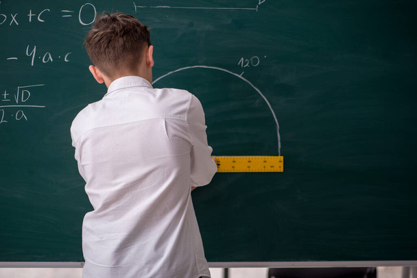 Schoolboy studying geometry in front of blackboard - Φωτογραφία, εικόνα