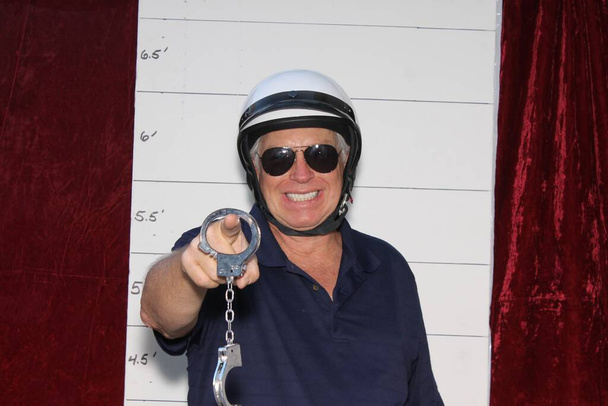 Photo Booth. Mug Shot Photo Booth. A Criminal is arrested and has his photo taken. Booking Photo. Police mug shots of a male criminal and his dog, standing in front of a Mug Shot Wall.  Under arrest. mug shot of man in Police Motorcycle Helmet. - Photo, Image