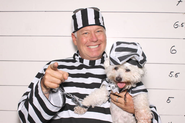 Photo Booth. Mug Shot Photo Booth. A Criminal is arrested and has his photo taken. Booking Photo. Police mug shots of a male criminal and his dog, standing in front of a Mug Shot Wall. Line Up. Under arrest. mug shot of middle aged man and his dog. - Photo, Image