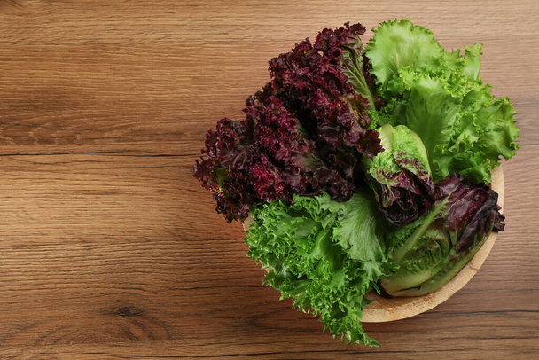 Different sorts of lettuce on wooden table, top view. Space for text - Fotó, kép
