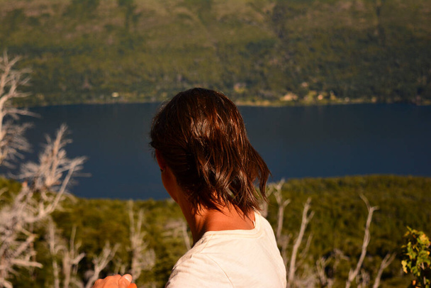 woman from behind watching lake and mountain on sunny day - Foto, afbeelding