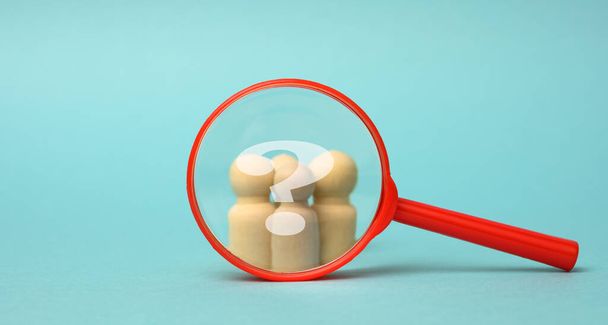 wooden figurines of men and a red magnifying glass on a blue background. Recruitment for the company, like-minded people and teamwork. Search for talent - Photo, Image