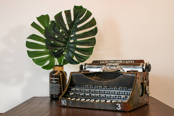 Vintage typewriter on the wooden table with tropical leaves - Photo, Image