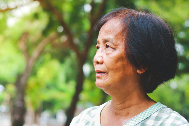 Азиатская пожилая женщина, стоящая в саду, чувствует себя счастливой. Счастливой пенсионной жизни. старшее сообщество. Копирование пространства - Фото, изображение