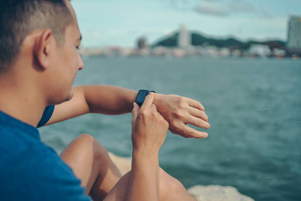 sport man checking at smartwatch during training and running in the park. Sport and technology concept. - Φωτογραφία, εικόνα