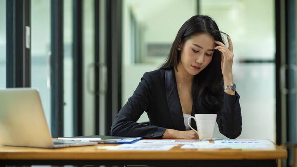 Бізнес-леді відчуває себе підкреслено з роботи, менеджер дивлячись фінансовий звіт на столі в офісі
 - Фото, зображення