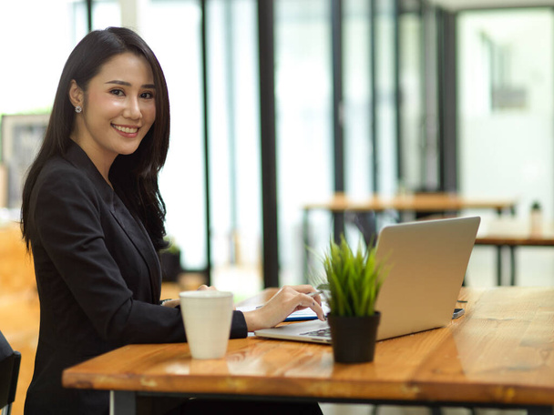 Mulher de negócios elegante em terno preto digitando no teclado do laptop no espaço de co-trabalho café, bela mulher em terno preto - Foto, Imagem