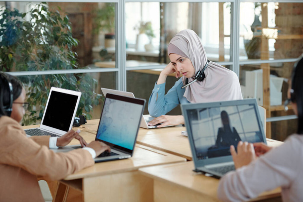 Yorgun Müslüman iş kadını dizüstü bilgisayarın önünde oturuyor. - Fotoğraf, Görsel