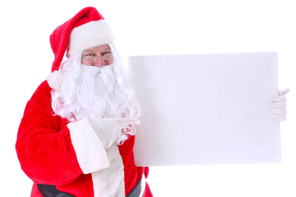 Christmas. Santa Claus. Santa Claus Portrait. Santa Claus Smiles holds a blank white sign. Room for text. Isolated on white. Clipping Path. Smiling traditional Santa Claus. Bearded smiling Santa Claus. Kind old Santa Claus. Christmas Season.  - Photo, Image