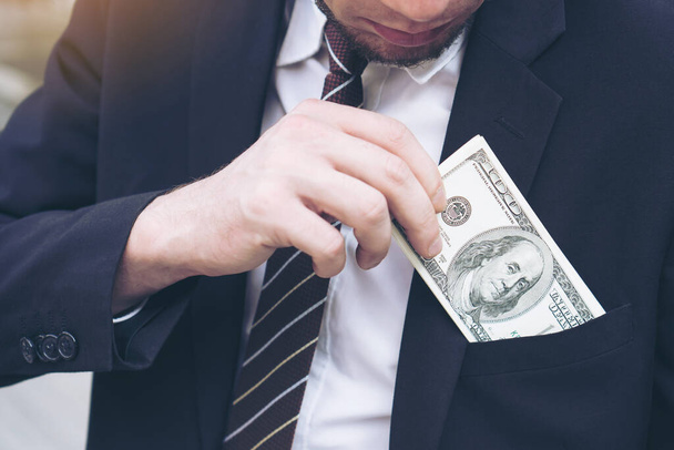 hombre de negocios Recogiendo dinero Billetes de dólar que sobresalen de su bolsillo, concepto de negocio de éxito - Foto, imagen