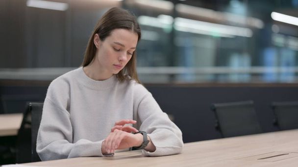 Όμορφη γυναίκα χρησιμοποιώντας Smart Watch στο γραφείο - Φωτογραφία, εικόνα