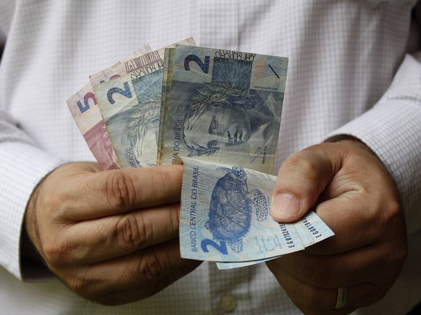 manos de un hombre sosteniendo y contando billetes brasileños - Foto, Imagen