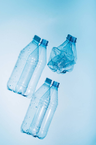 Botellas de plástico con agua y vacío utilizadas sobre fondo azul. Reciclaje de plástico reciclable. Protección medioambiental - Foto, Imagen