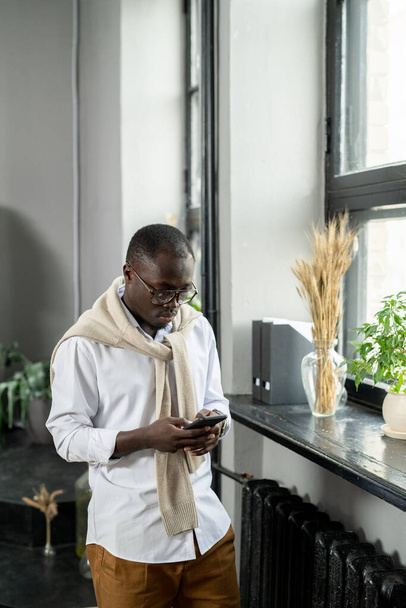 Mladý africký podnikatel rolování v smartphonu v úřadu - Fotografie, Obrázek