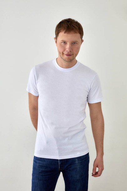 Jeune homme positif en tenue décontractée debout sur fond blanc - Photo, image