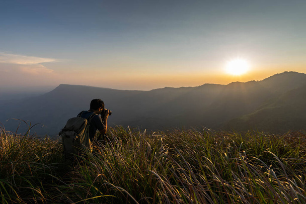 mies matkailija matkailija valokuvaaja seisoo kalliolla vuoren auringonlaskun aikana - maisema auringonlasku Thaimaa - Valokuva, kuva