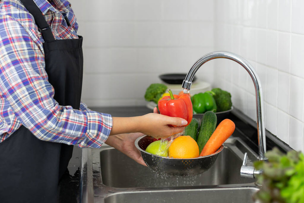 Washing vegetables in the kitchen sink - 写真・画像