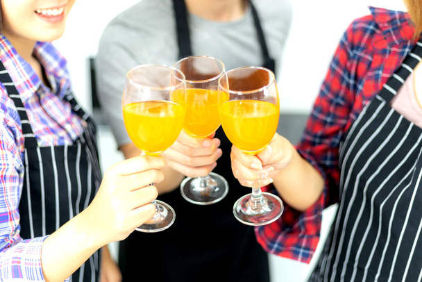 Τρεις φίλοι απολαμβάνουν το ποτήρι του πάρτι, πίνοντας χυμό πορτοκάλι κοκτέιλ μαζί - Φωτογραφία, εικόνα