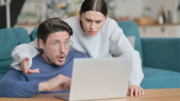 Mixed Race Couple having Loss While using Laptop Together at Home  - 写真・画像
