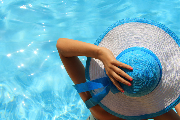 Giovane signora con cappello blu bianco a bordo piscina
 - Foto, immagini