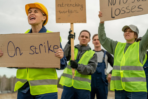 Grupo de empleados en ropa de trabajo que llevan pancartas durante la huelga - Foto, Imagen
