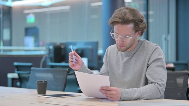 若い男はオフィスで文書を読む - 写真・画像