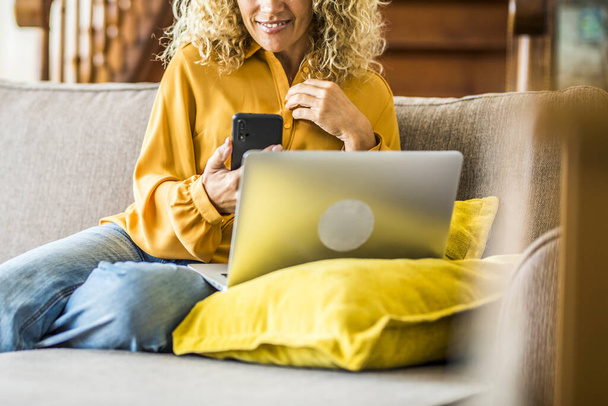 Close-up van de vrouw met behulp van moderne smartphone thuis zitten op de bank genieten van internet verbinding draadloos - Foto, afbeelding