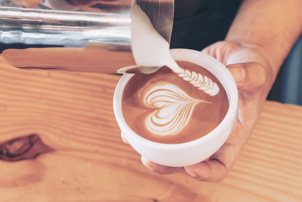 Kahve dükkanında kahvecinin sütünü dolduran erkek eli yakın plan görüntüsü. - Fotoğraf, Görsel