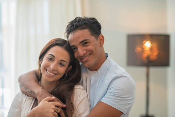 Νεαρό διαφυλετικό ζευγάρι χιλιετή αγκαλιά με αγάπη στο σπίτι στο σαλόνι - Φωτογραφία, εικόνα