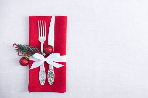 Χριστουγεννιάτικο τραπέζι με μια κόκκινη πετσέτα στο λευκό τραπεζομάντηλο. Στο πάνω μέρος. Αντιγραφή χώρου. - Φωτογραφία, εικόνα