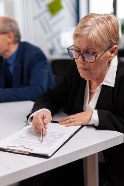 Старша бізнес-леді читає документи в конференц-залі
 - Фото, зображення