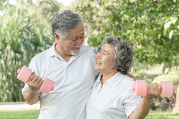 Alegre anciano asiático hombre y anciano asiático mujer con mancuerna para el entrenamiento en el parque, Sonriendo con buena salud juntos - Foto, Imagen