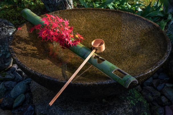 Fuente de agua de Tsukubai en el jardín japonés en el templo de Zuiganzan Enkouji, Kioto, Japón en otoño. Con hojas de arce rojo en el lavabo. - Foto, imagen