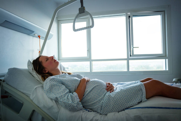 Woman in hospital bed in pain during labor in maternity ward - Photo, image