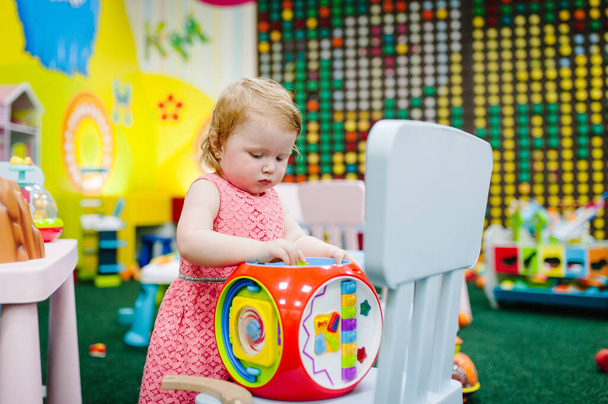 Happy children, a little girl are playing educational toys in the children's playroom on their birthday. Kindergarten. Nursery school. Party in kids amusement park and play center indoor. - Photo, Image