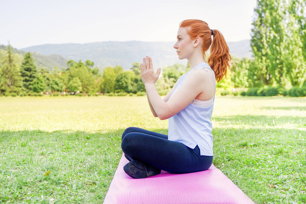 Portrét mladé ženy cvičící jógu ve veřejném parku - Fotografie, Obrázek