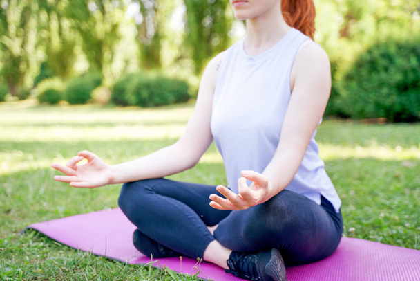 Portrait of young woman practicing yoga in public park - Photo, Image