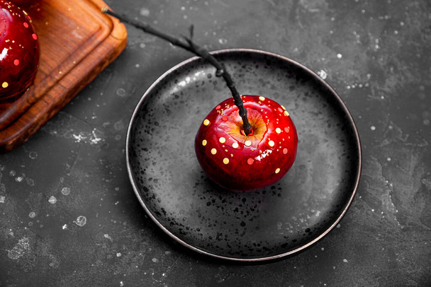 砂糖の装飾が施されたキャラメルの赤いリンゴ、お祝いのハロウィンテーブルのための元の御馳走 - 写真・画像