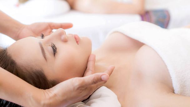 bela e saudável jovem mulher relaxante com massagem facial no salão de beleza spa - Foto, Imagem