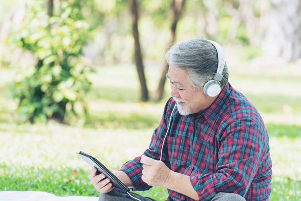 Старший по возрасту человек счастлив, слушая музыку в наушниках, изолированных на белом фоне - Фото, изображение