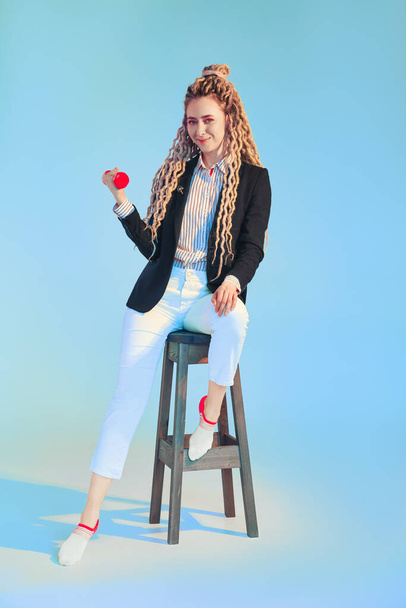 Woman power concept - girl in jeans and jacket with dreadlocks pumps dumbbell - Фото, зображення
