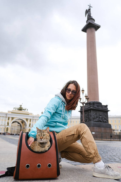 Cat ο ταξιδιώτης με μια νεαρή γυναίκα στο παρασκήνιο των αξιοθέατων της Αγίας Πετρούπολης. - Φωτογραφία, εικόνα
