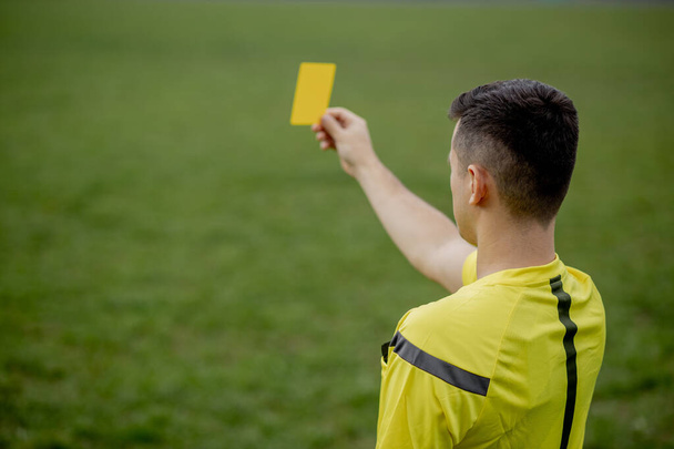 Referee showing a red card to a displeased football or soccer player while gaming. Concept of sport, rules violation, controversial issues, obstacles overcoming - Foto, Bild